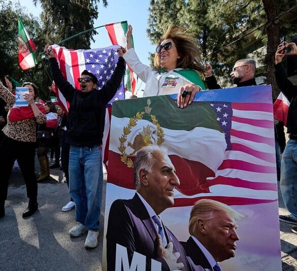 An anti-Iranian regime protestor holds a placard bearing images depicting the son of Iran's Last Shah and now key opposition figure, Reza Pahlavi and US President, Donald Trump as protestors gather in front of the Iranian Embassy in Athens on March 1, 2026, during a protest in support of the US and Israel attack on Iran and the killing of Iran's supreme leader. Iranian state television confirmed the death of Iran's supreme leader Ayatollah Ali Khamenei on February 28, 2026, after US President said he had been killed. The announcement came after the United States and Israel started launching waves of strikes against targets in Iran, sparking swift retaliation by the Islamic Republic. (Photo by Aggelos NAKKAS / AFP via Getty Images)
