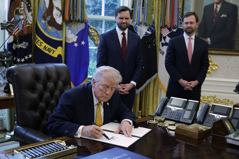 WASHINGTON, DC - MARCH 16: U.S. President Donald Trump signs a document as Vice President JD Vance (C) and Federal Trade Commission Chairman Andrew Ferguson look on during a White House signing ceremony in the Oval Office of the White House on March 16, 2026 in Washington, DC. Trump signed an executive order to create a task force on fraud which will be lead by Vice President J.D. Vance. (Photo by Alex Wong/Getty Images)