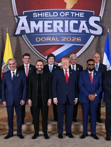 TOPSHOT - US President Donald Trump (C) stands with, (L/R), Trinidad and Tobago's Prime Minister Kamla Persad-Bissessar, Santiago Peña, President of the Republic of Paraguay, Luis Abinader, President of the Dominican Republic, Rodrigo Paz Pereira, President of Bolivia, Nayib Bukele, President of El Salvador, Javier Milei, President of Argentina, José Raúl Mulino, President of Panama, Mohamed Irfaan Ali, President of Guyana, Nasry "Tito" Asfura, President of Honduras, Rodrigo Chaves Robles, President of Costa Rica, José Antonio Kast, President-elect of Chile, and Daniel Roy Gilchrist Noboa Azín, President of Ecuador, during a group photograph at the start of the "Shield of the Americas" Summit at Trump National Doral in Miami, Florida, March 7, 2026. President Trump is hosting a dozen right-wing leaders from Latin America and the Caribbean to discuss issues facing the region, from organized crime to illegal immigration. The summit also aims to serve Washington by boosting US interests in the region and curbing those from foreign powers like China. (Photo by SAUL LOEB / AFP via Getty Images)