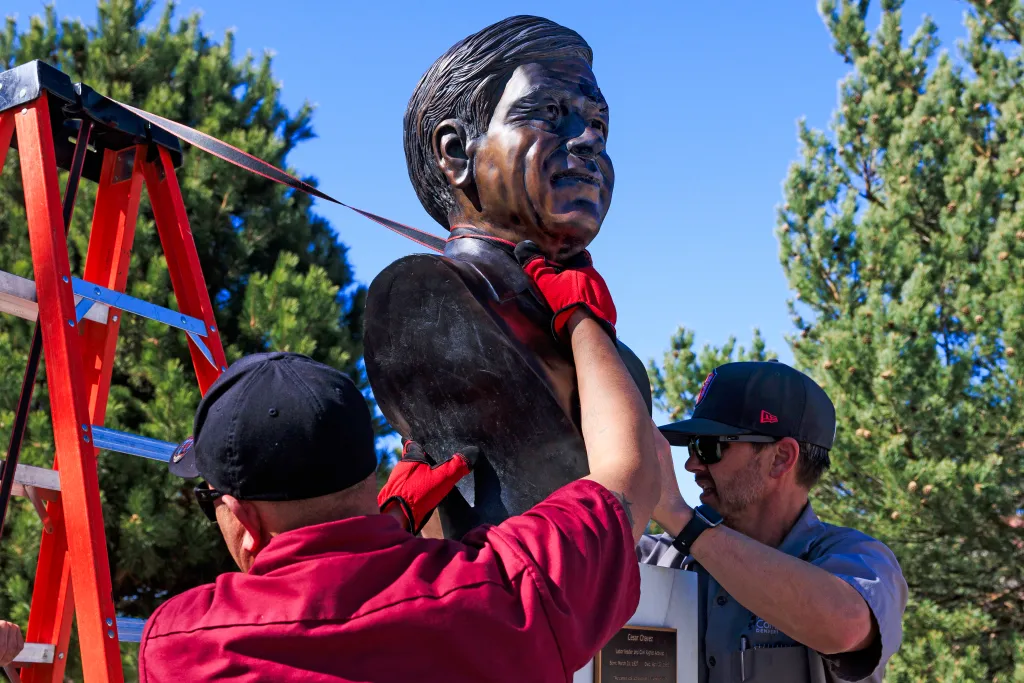 Workers removing a bust of Cesar Chavez from a park.
