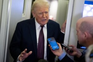 Donald Trump speaks to reporters, one of whom records him on a smartphone.