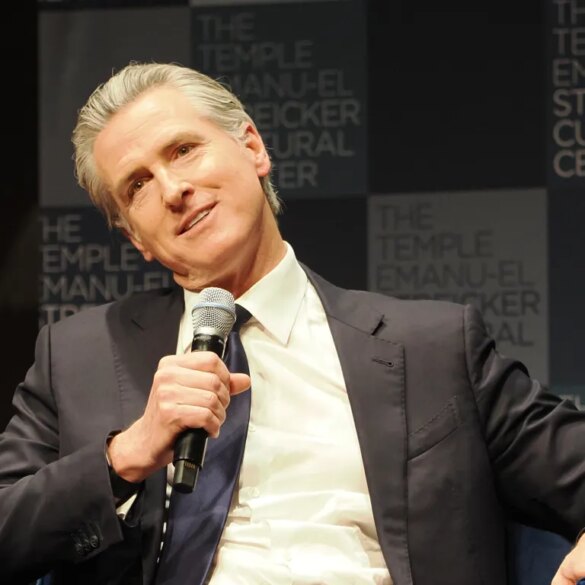 Gavin Newsom speaking at Temple Emanu-El, holding a microphone.