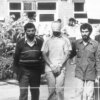 A blindfolded and bound hostage is led by Iranian students in front of a building.