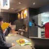 A woman interacting with a humanoid robot wearing a McDonald's vest at a counter.