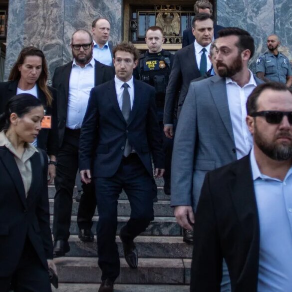 Mark Zuckerberg, in a dark suit, walks down courthouse steps surrounded by security.