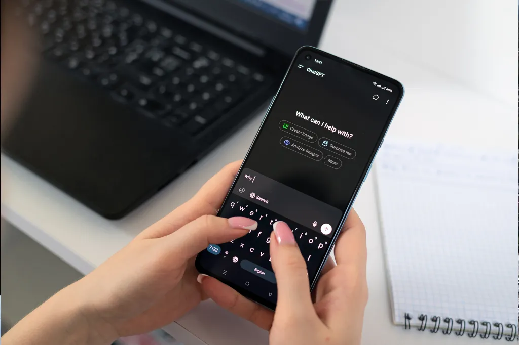 A person using the ChatGPT app on a smartphone, typing "why" into the search bar.